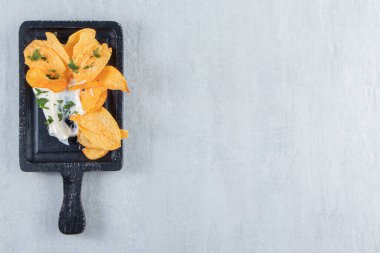 Tuzlu çıtır cips ve siyah kesme tahtasında taze yoğurt. Yüksek kalite fotoğraf