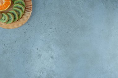 Ahşap bir tabakta dilimlenmiş portakal ve kivi, mermer arka planda. Yüksek kalite fotoğraf