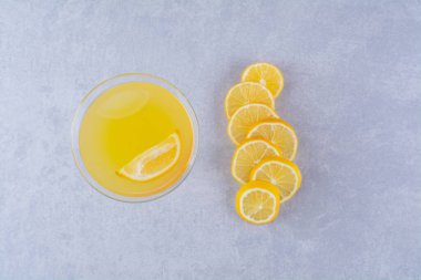 Mermer zemin üzerinde, bir bardak portakal suyunun yanında taze dilimlenmiş limon. Yüksek kalite fotoğraf