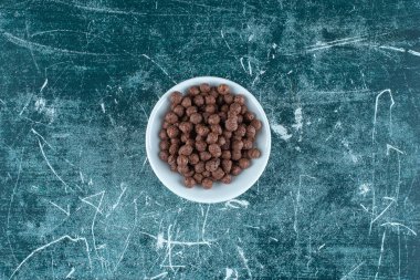 Mavi arka planda, bir kasede çikolatalı mısır topları. Yüksek kalite fotoğraf