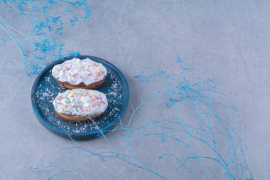 Mavi ahşap bir tahtanın üzerine renkli süslemeler ve krema serpiştirilmiş iki taze kek. Yüksek kalite fotoğraf