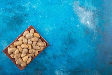 Kabuklu bademler bir tabakta, mavi arkaplanda. Yüksek kalite fotoğraf