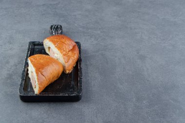 Siyah tahtada iki parçaya bölünmüş sosisli hamur işi. Yüksek kalite fotoğraf