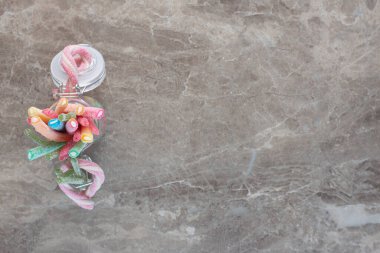 Gri arkaplanda kavanozda renkli kurdele şekerlemelerinin üst görüntüsü. Yüksek kalite fotoğraf