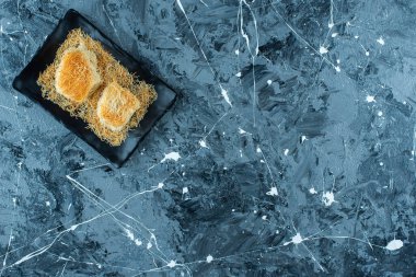 Siyah tabakta, mavi arkaplanda Türk tatlısı kadayif. Yüksek kalite fotoğraf