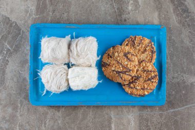 Ev yapımı kurabiyeler ve ahşap bir tabakta Türk pamuk şekeri, mavi arka planda. Yüksek kalite fotoğraf