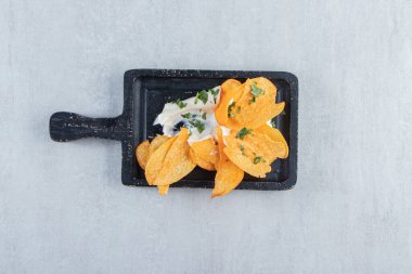 Tuzlu çıtır cips ve siyah kesme tahtasında taze yoğurt. Yüksek kalite fotoğraf