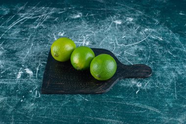 Kesme tahtasındaki olgunlaşmamış limonlar, mermer arka planda. Yüksek kalite fotoğraf