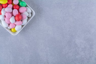 Gri arkaplanda renkli fasulye şekerleriyle dolu beyaz bir tahta. Yüksek kalite fotoğraf