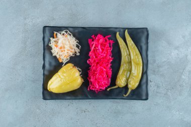 Mavi arka planda plastik bir tabakta mayalanmış biber ve lahana turşusu. Yüksek kalite fotoğraf