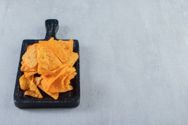 Taş zeminde siyah kesme tahtasındaki baharatlı üçgen çipler. Yüksek kalite fotoğraf