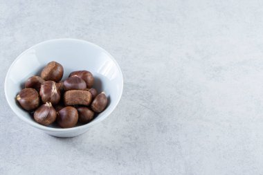 Beyaz kase taştan arka planda bir sürü çıtır kestane. Yüksek kalite fotoğraf