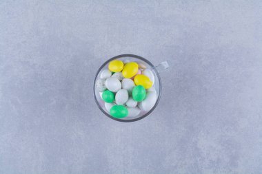 Gri arka planda bir bardak dolusu renkli fasulye şekeri. Yüksek kalite fotoğraf.