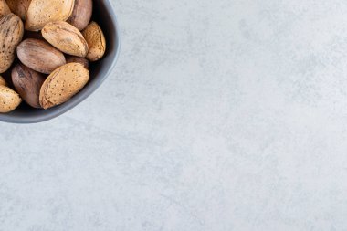 Taş zemin üzerinde kabuklu badem ve ceviz dolu mavi kase. Yüksek kalite fotoğraf