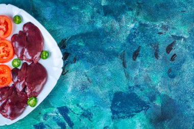 Taze sebze ve tavuk ciğeri tabakta, mavi arka planda. Yüksek kalite fotoğraf