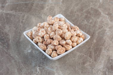 Kahverengi lezzetli şekerler gri arka planda beyaz tabakta. Yüksek kalite fotoğraf