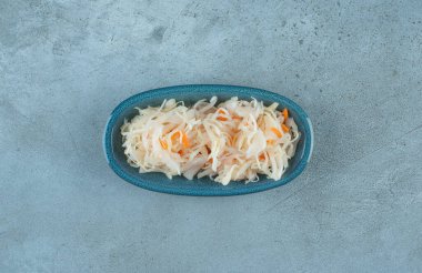 Mavi arka planda tahtadan bir tabakta havuçlu mayalanmış lahana turşusu. Yüksek kalite fotoğraf