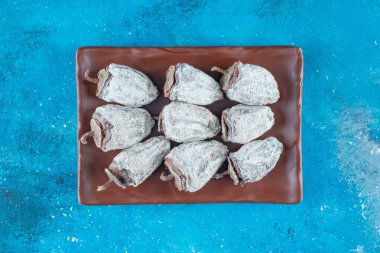 Mavi arka planda, tabakta kurutulmuş hurma. Yüksek kalite fotoğraf