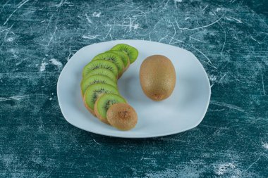  Dilimlenmiş ve tüm kivi tabakta, mermer zemin üzerinde. Yüksek kalite fotoğraf