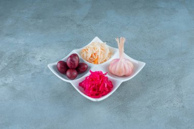 Mermer zemin üzerinde, bir tabakta çeşitli mayalanmış sebzeler. Yüksek kalite fotoğraf