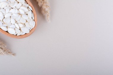 Beyaz arka planda organik kabak tohumlarıyla dolu bir kâse. Yüksek kalite fotoğraf