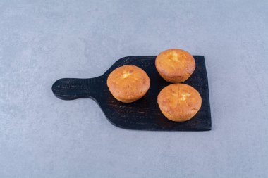 Üç tatlı taze kekten oluşan siyah ahşap bir tahta. Yüksek kalite fotoğraf