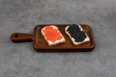 Tahta tahtada kırmızı ve siyah havyarlı sandviçler. Yüksek kalite fotoğraf