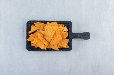 Taş zeminde siyah kesme tahtasındaki baharatlı üçgen çipler. Yüksek kalite fotoğraf