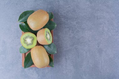 Tahta tabakta yapraklar ve kivi, mermer arka planda. Yüksek kalite fotoğraf