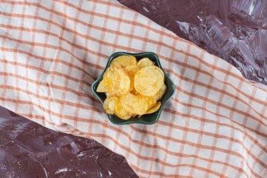 Çay havlusunda, mermer arka planda, bir kasede nefis patates cipsi. Yüksek kalite fotoğraf