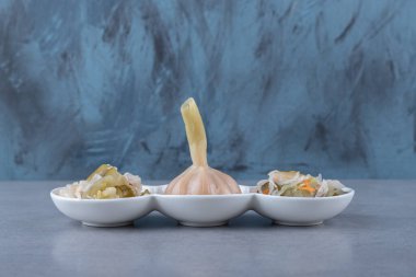 Lahana turşusu ve sarımsak bir kasede, mermer arka planda. Yüksek kalite fotoğraf