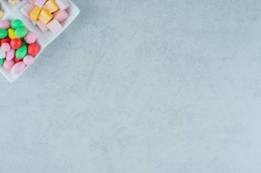 Beyaz arka planda lokum ve renkli şekerlerle dolu beyaz bir tahta. Yüksek kalite fotoğraf