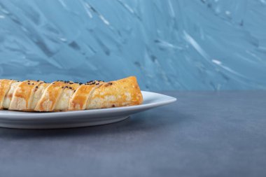 Mermer arka planda, tabakta kıymalı küçük bir pasta. Yüksek kalite fotoğraf