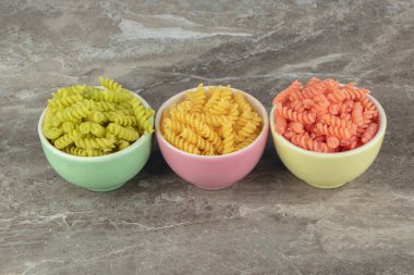 Mermer zemin üzerinde üç kase renkli fusilli. Yüksek kalite fotoğraf