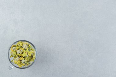 Taş arka planda sarı çiçeklerle dolu cam bardak. Yüksek kalite fotoğraf