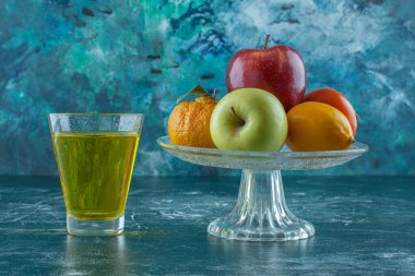 Meyveler cam kaidede meyve suyunun yanında, mavi arkaplanda. Yüksek kalite fotoğraf