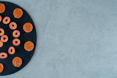 Halka şeklinde yuvarlak turuncu marmelat ve şekerli turuncu jöle şeklinde siyah bir tahta. Yüksek kalite fotoğraf