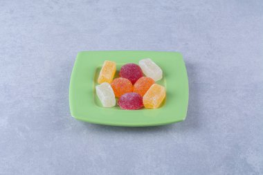 Gri arka planda şekerle dolu yeşil bir tabak. Yüksek kalite fotoğraf