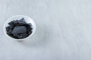 Beyaz kase, taştan arka planda tuzlanmış siyah cips. Yüksek kalite fotoğraf