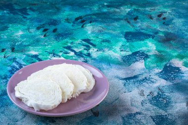 Mavi arka planda, bir tabak üzerinde dilimlenmiş lahana gösterisi. Yüksek kalite fotoğraf