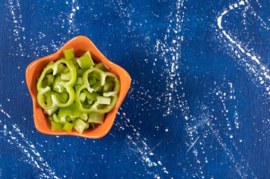 Mermer zemin üzerinde turuncu kase taze yeşil dolma biber halkaları. Yüksek kalite fotoğraf