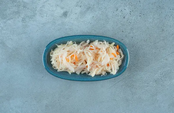 Mavi arka planda tahtadan bir tabakta havuçlu mayalanmış lahana turşusu. Yüksek kalite fotoğraf