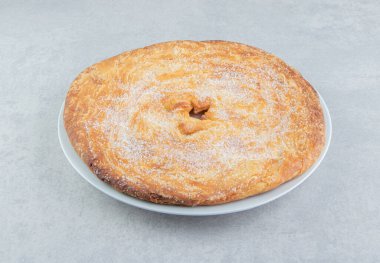 Beyaz tabakta pudrayla süslenmiş yuvarlak pasta. Yüksek kalite fotoğraf