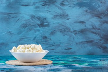 Mavi arka planda bir kase karnabahar. Yüksek kalite fotoğraf