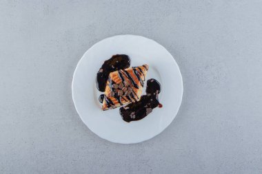 Beyaz tabağa yerleştirilmiş çikolata şurubuyla süslenmiş tatlı pasta. Yüksek kalite fotoğraf