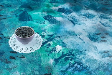 Kabuklarda soyulmamış ayçiçeği tohumları, bardak altlığında, mavi arka planda. Yüksek kalite fotoğraf