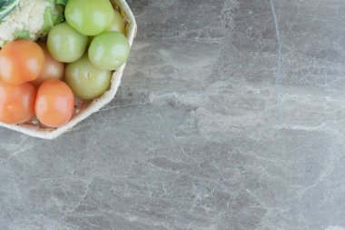 Sağlıklı yiyeceklerin en üst görüntüsü. Gri sepetin üzerinde yeşil ve kırmızı domatesler. Yüksek kalite fotoğraf