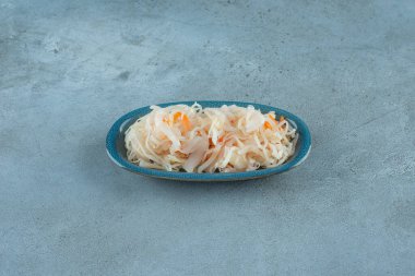 Mavi arka planda tahtadan bir tabakta havuçlu mayalanmış lahana turşusu. Yüksek kalite fotoğraf