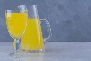 Mermer zemin üzerinde bir bardak portakal suyu bulunan bir sürahi portakal suyu. Yüksek kalite fotoğraf