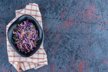 Masa örtüsünde sebze salatası olan siyah bir tabak. Yüksek kalite fotoğraf